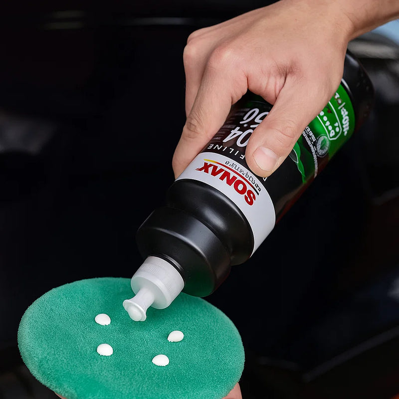 Auftragen der Sonax Profiline EX 04-06 Finish Politur auf ein Polierpad vor der Anwendung am Fahrzeug.