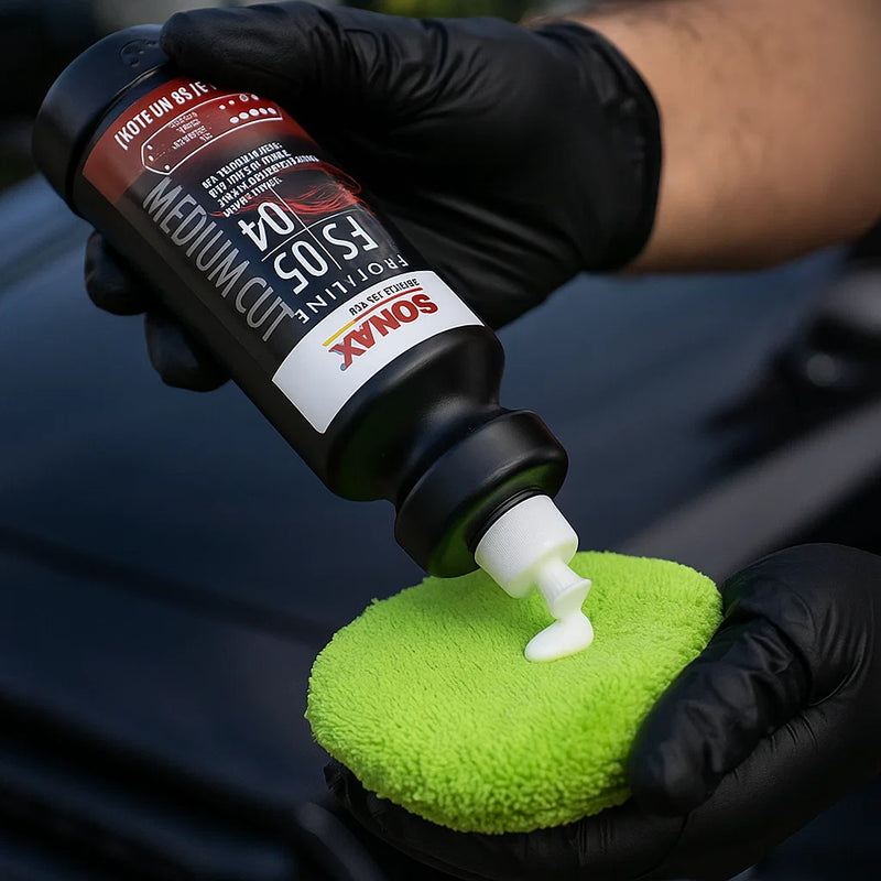 Detailer trägt Sonax Profiline FS 05-04 Medium Cut Politur mit Applikatorpad auf den Autolack auf.