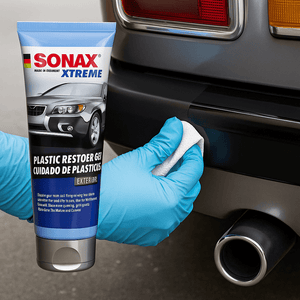 Ein Anwender mit Gummihandschuh trägt SONAX XTREME KunststoffGel gezielt auf die Kunststoff-Heckstoßstange eines Oldtimers auf – für intensive Farbauffrischung und langanhaltenden Schutz.